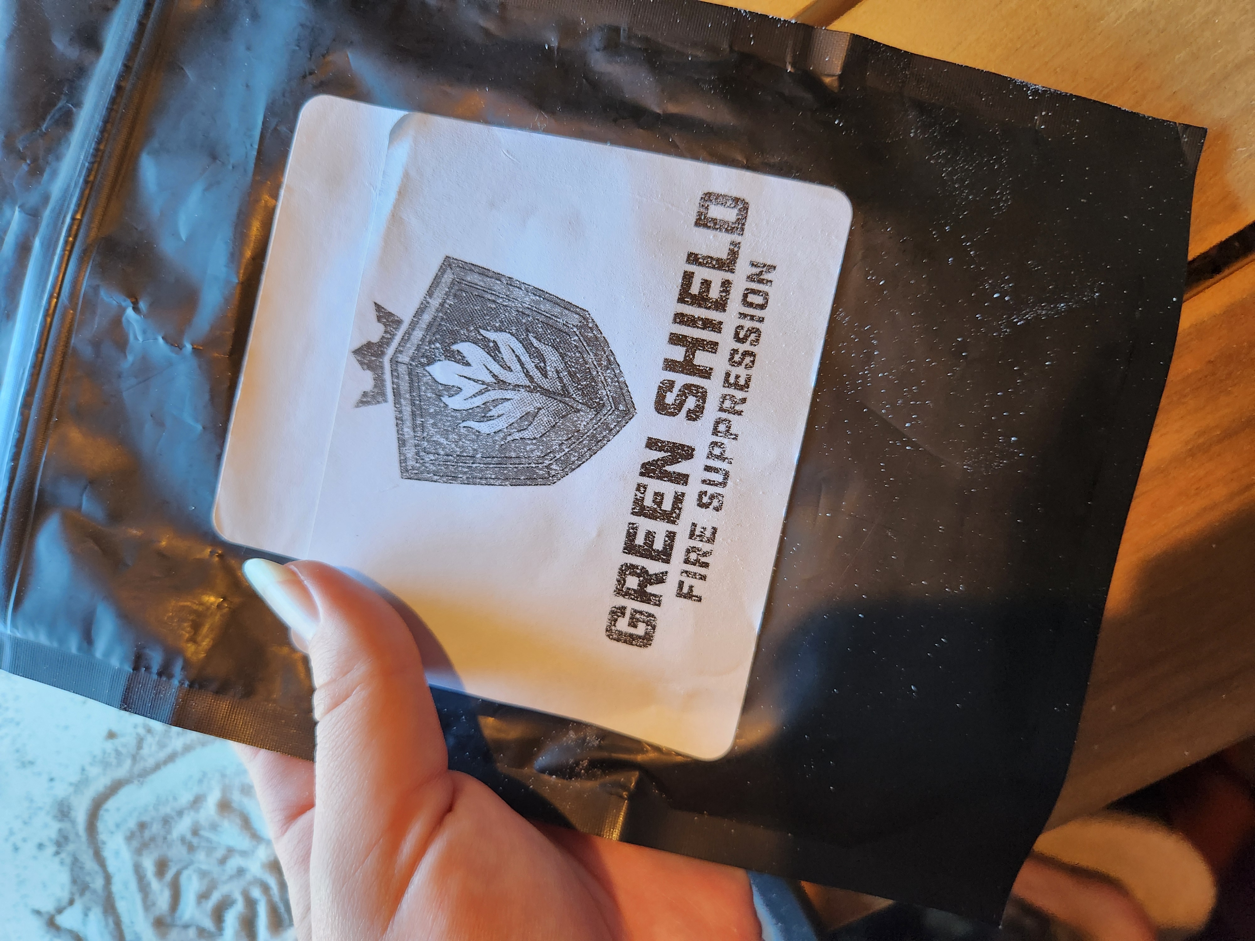 Trinity holding the Green Shield Fire sample package containing powdered hydrogel; just add water for fire suppression.